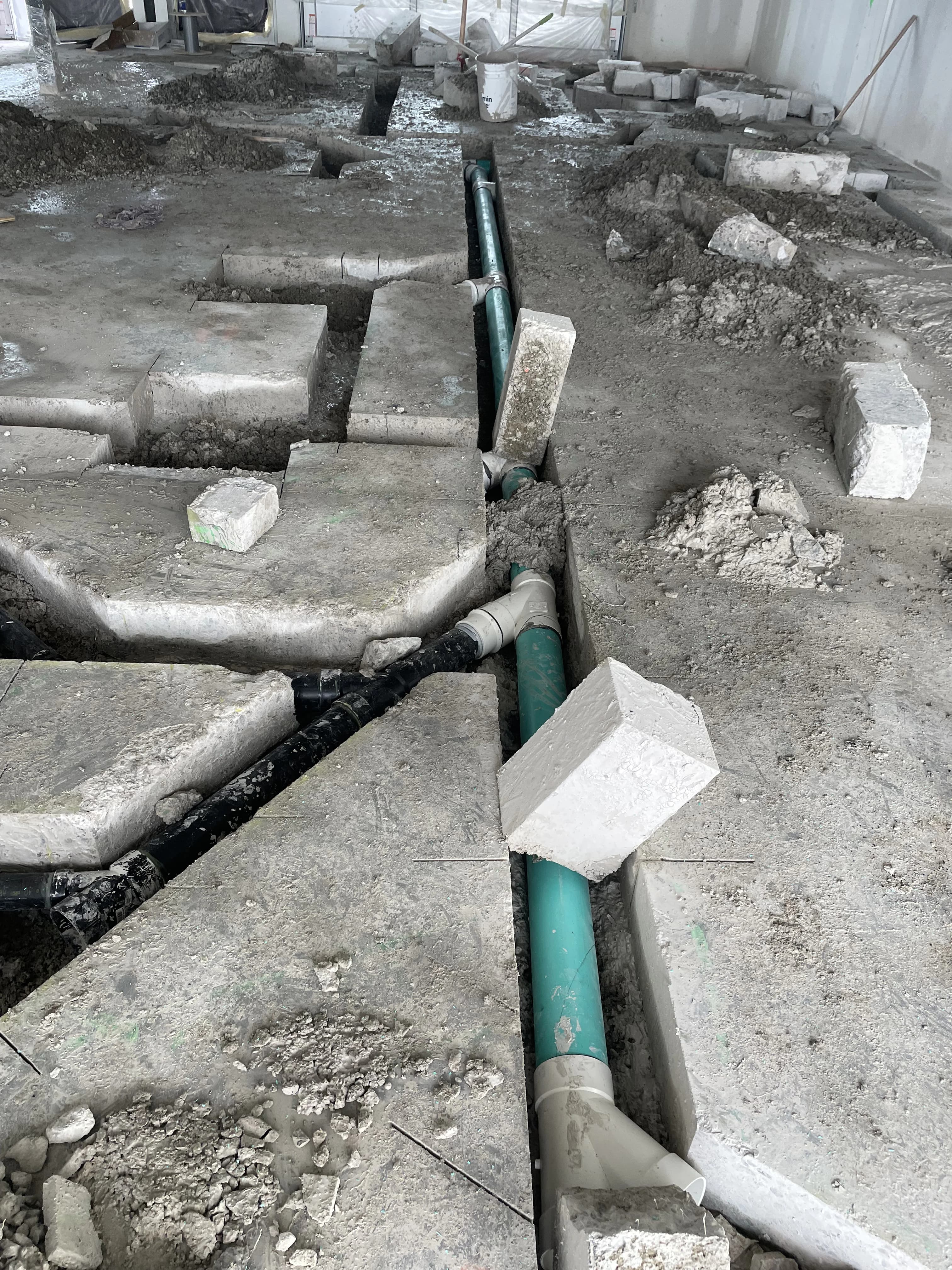 Sewer trunk line repair in Ajax with long green PVC in a trench and block supports