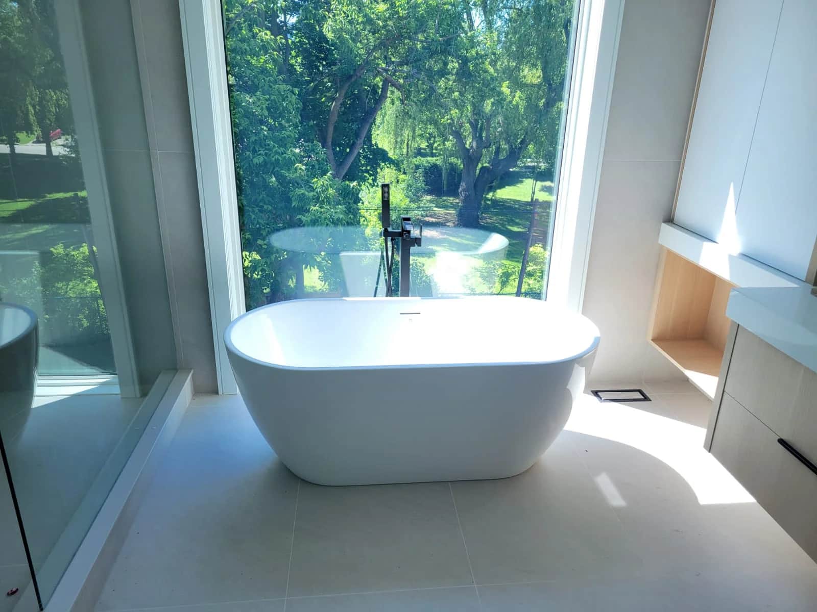 Luxury bathroom remodel in Ajax with a freestanding tub, floor-mounted filler, and garden window view.