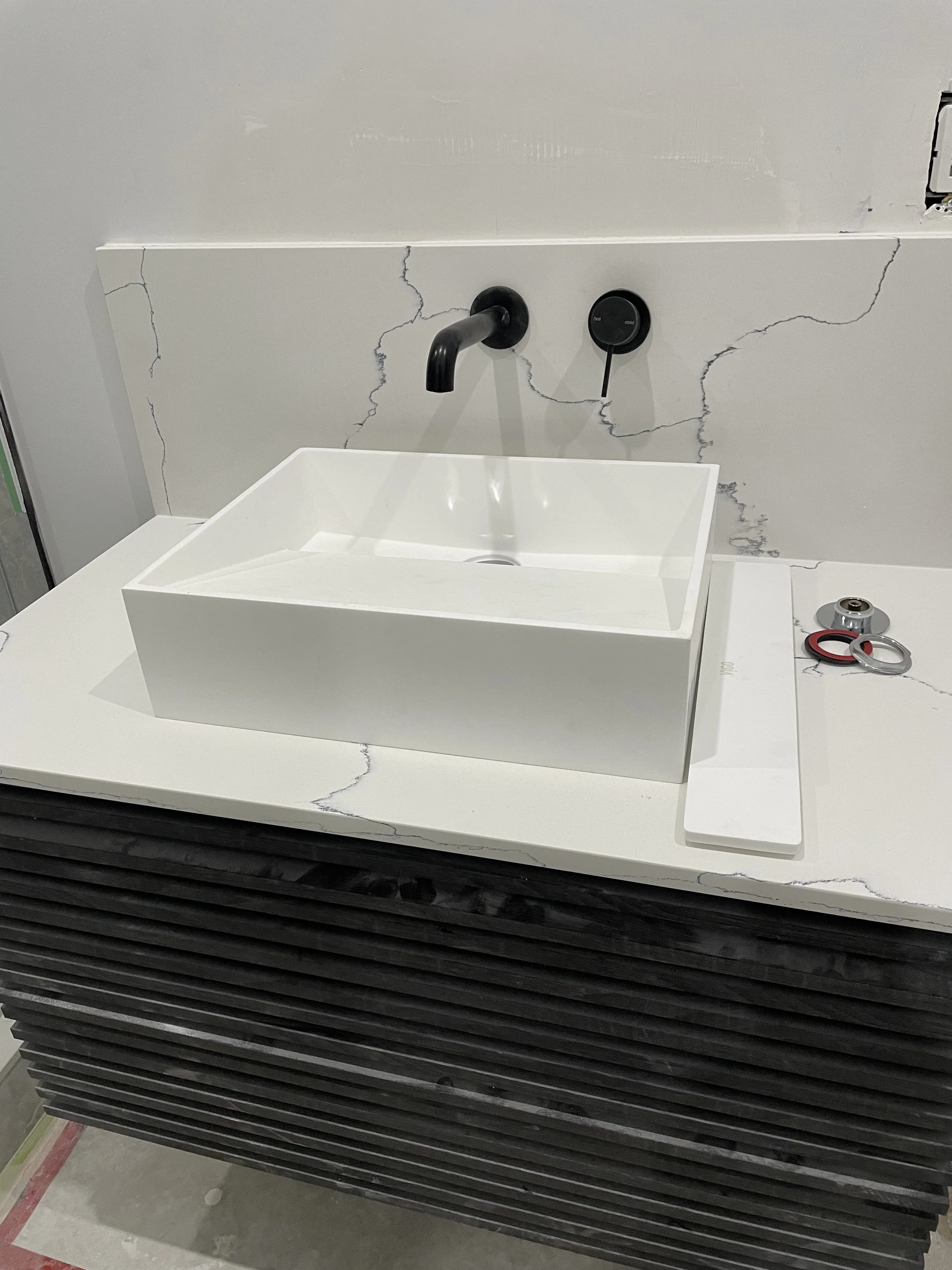Bathroom remodel in Ajax with a wall-mounted black faucet, vessel sink, and slatted floating vanity.