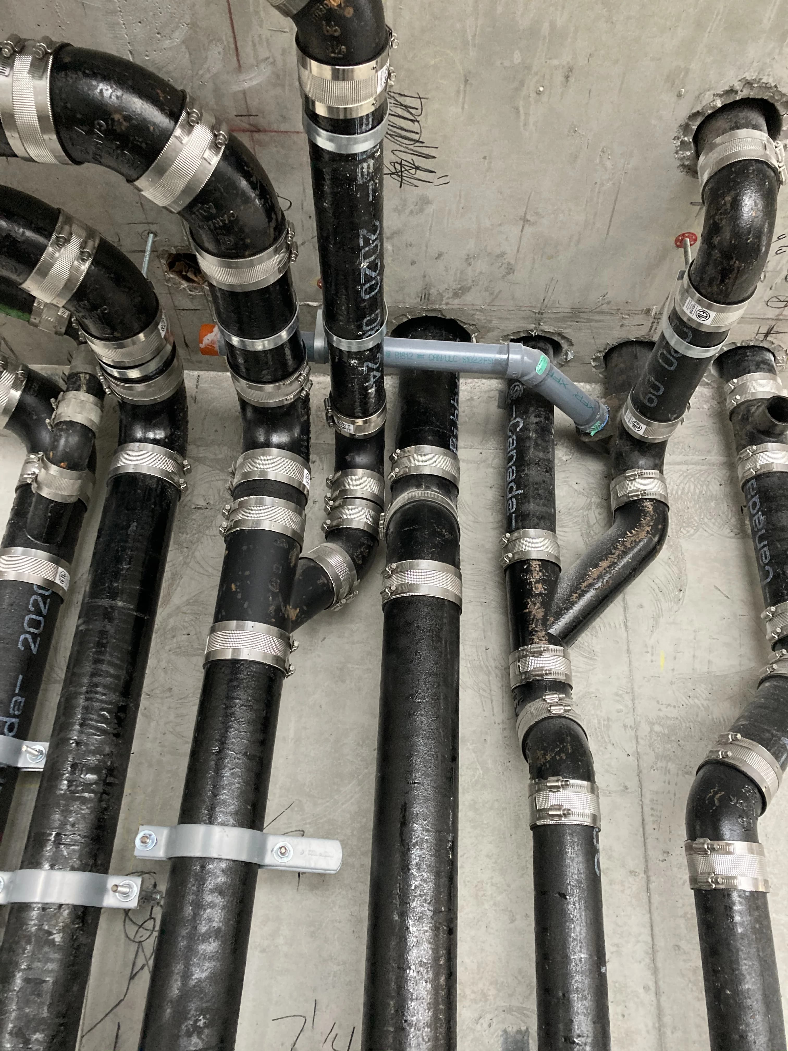Cast iron ceiling stacks and no-hub couplings on a commercial plumbing job in Ajax