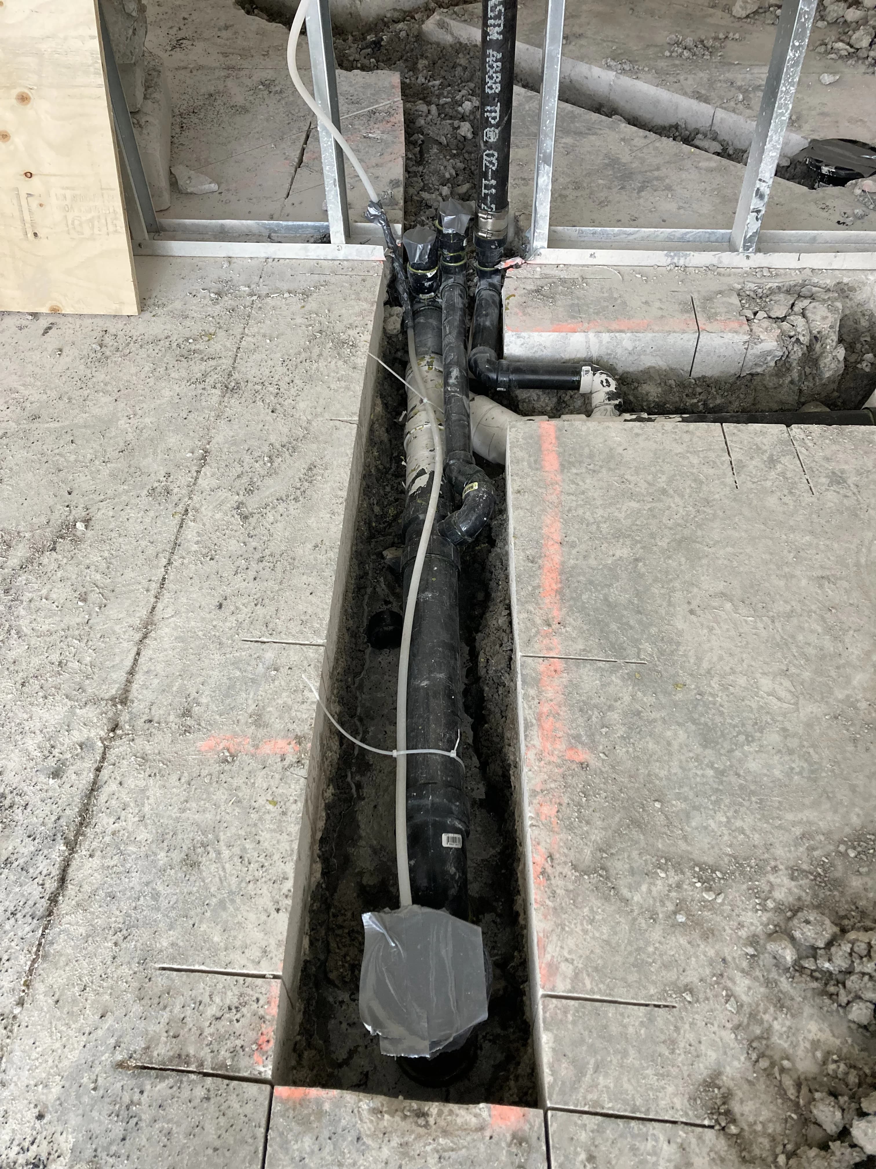 Commercial slab drain trench rough-in in Ajax with green PVC and cleanouts before pour