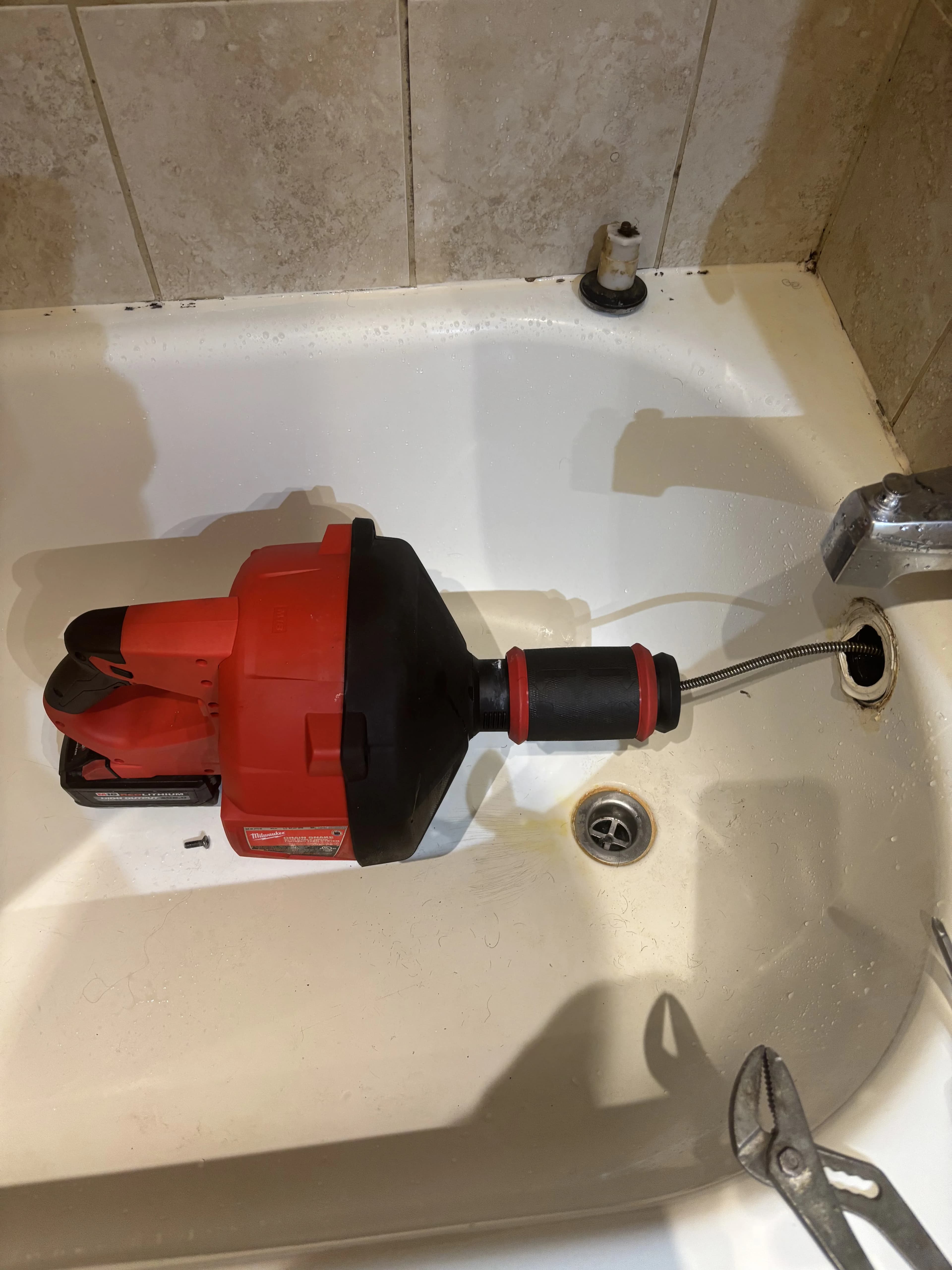 Power snake drain cleaning at a bathtub drain in an Ajax home