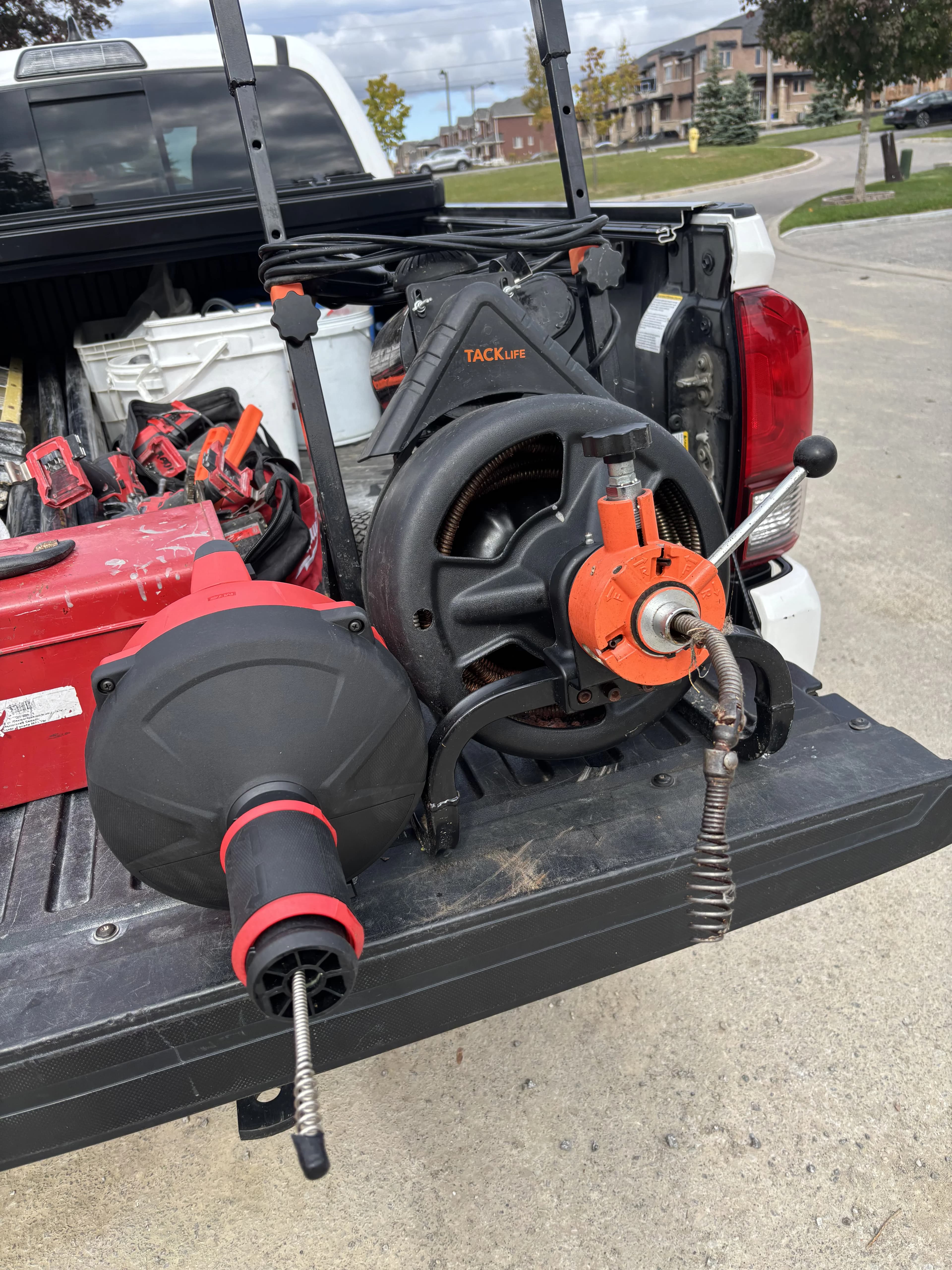 Portable drum augers on a service truck tailgate for drain cleaning in Ajax.