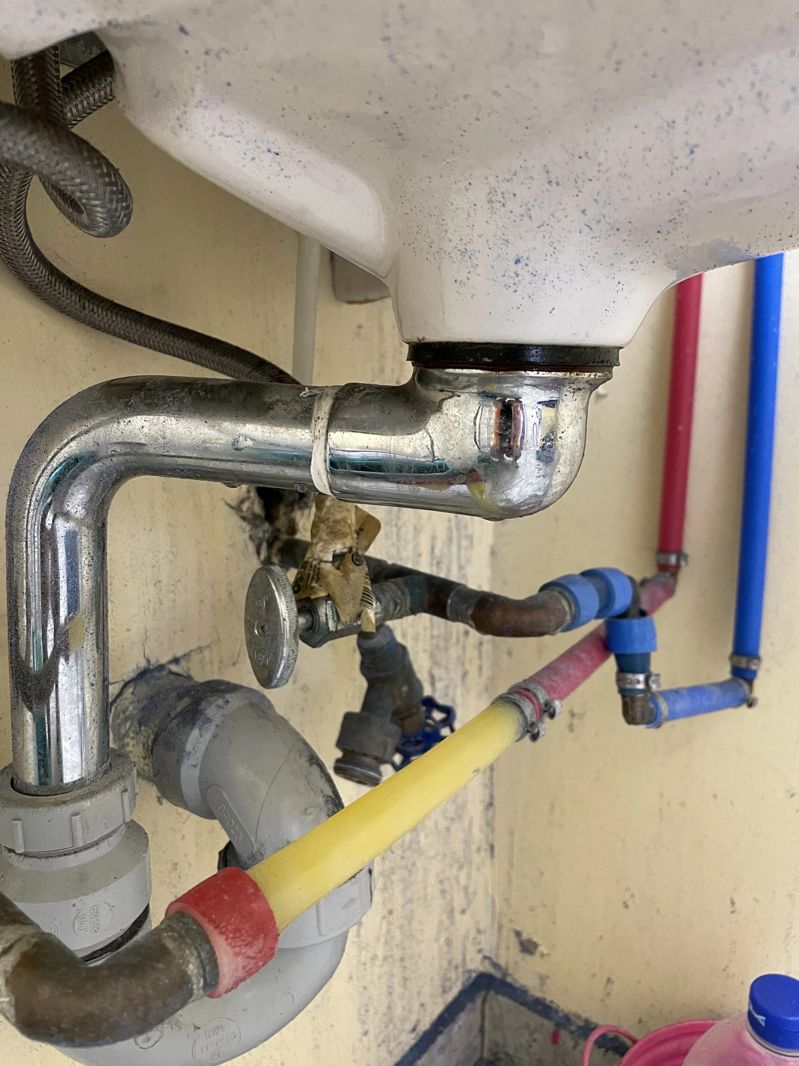 Emergency plumbing repair in Ajax under a kitchen sink with PEX supply lines and a chrome P-trap
