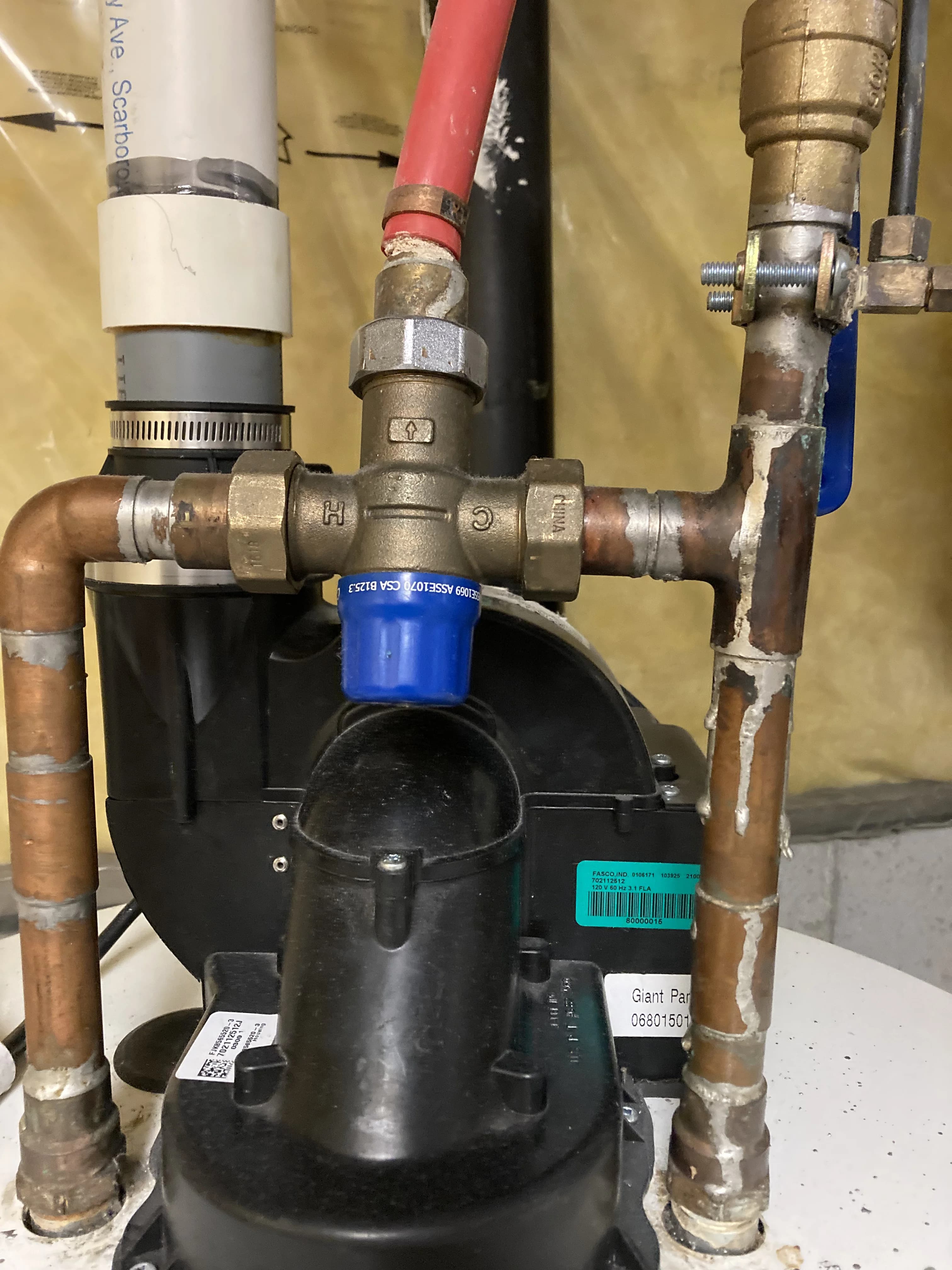 Electric water heater service in Ajax with a thermostatic mixing valve and copper connections on the tank top.
